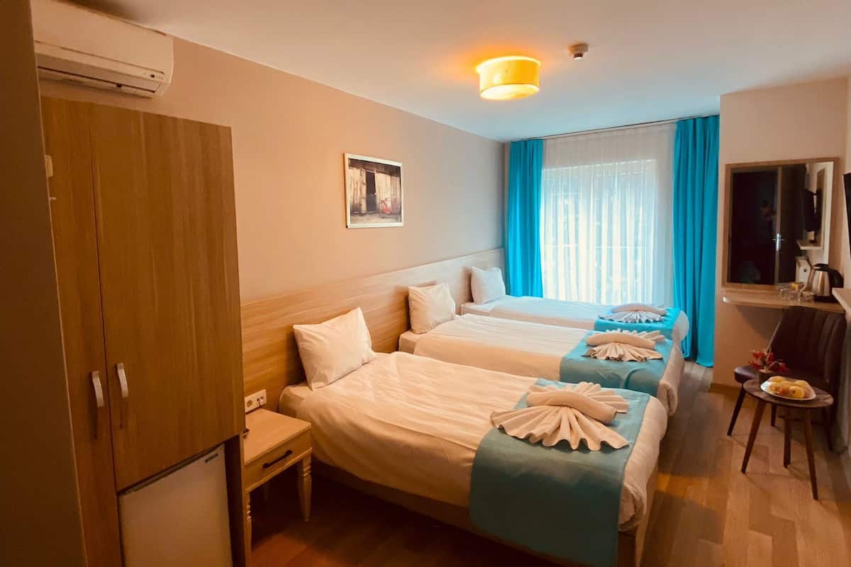 Ein Hotelzimmer mit zwei Betten, einem Kleiderschrank, einem Schreibtisch, einem Stuhl und einem Fernseher.