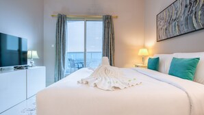 Hotelkamer met een groot bed, een flatscreen televisie, uitzicht op een balkon en een schilderij aan de muur.