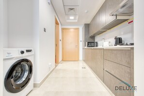 Une cuisine moderne équipée d’un lave-linge, d’un four à micro-ondes et d’une machine à café.