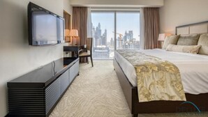 A hotel room with a bed, a desk, a television, and a view of the city skyline.