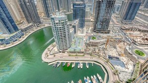 A high-rise building with a marina and construction cranes.