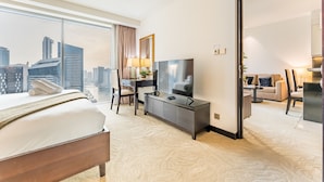 Ein Hotelzimmer mit Bett, Schreibtisch, Fernseher und Blick auf die Stadt.