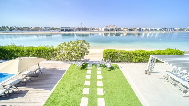 A pool area with a clear view of the beach and ocean, a pathway leading to the pool, and lounge chairs and umbrellas. - Signature 6BR Villa with Assistant Room and Private Pool in Frond F Palm Jumeirah by Deluxe Holiday Homes (Dubai)