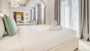 A spacious bedroom with a large bed, a modern chandelier, and a view of a cityscape through large windows. - Signature 6BR Villa with Assistant Room and Private Pool in Frond F Palm Jumeirah by Deluxe Holiday Homes (Dubai)