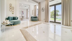 A spacious living area with a large window, a round coffee table, and two green sofas. - Signature 6BR Villa with Assistant Room and Private Pool in Frond F Palm Jumeirah by Deluxe Holiday Homes (Dubai)