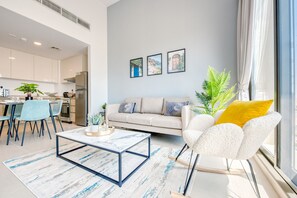 A modern living room with a sofa, a coffee table, and a dining area.