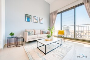 A modern living room with a sofa, coffee table, and a balcony with outdoor furniture.