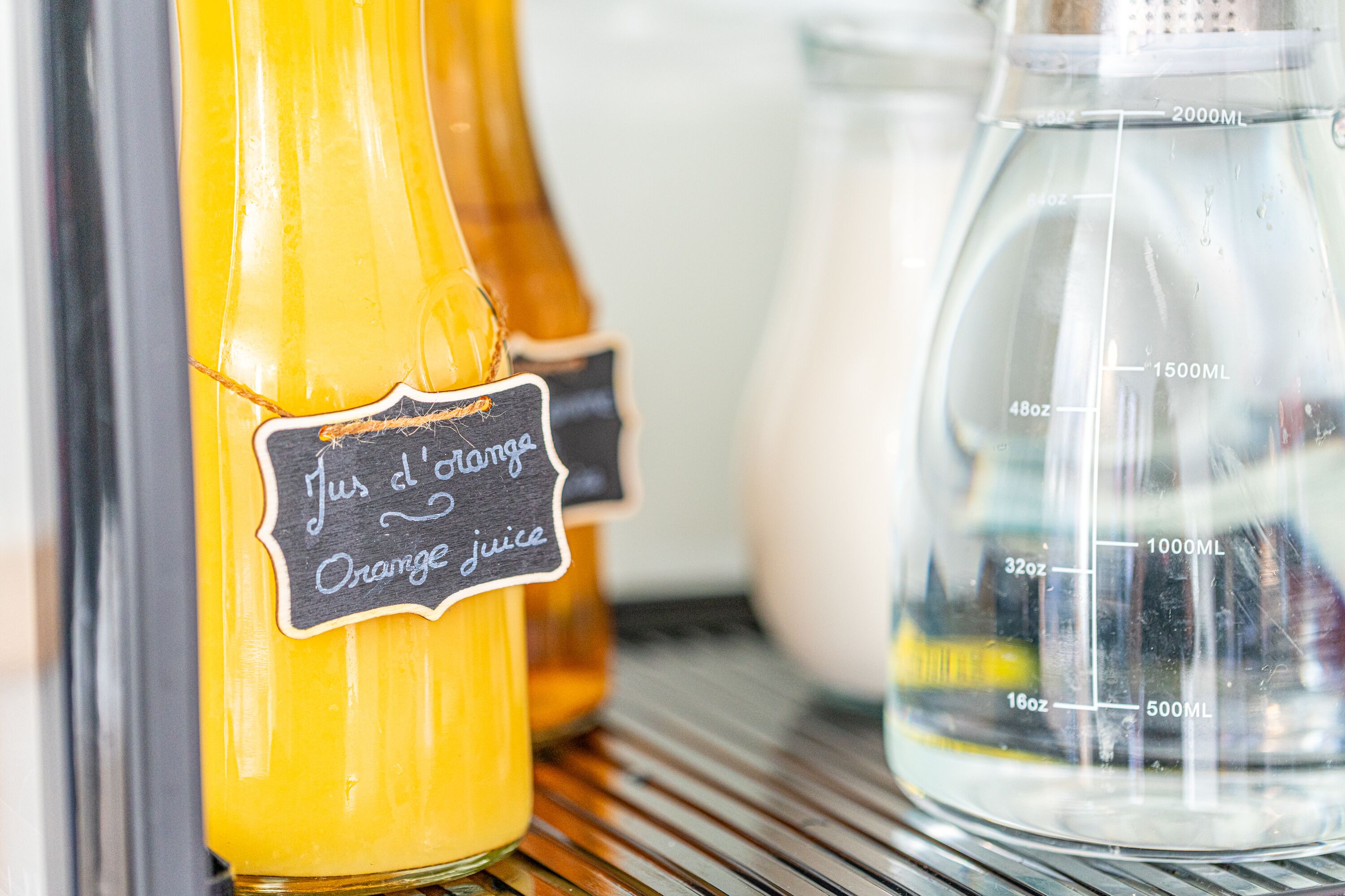 Une étagère avec des bouteilles de jus d’orange et un verre doseur.