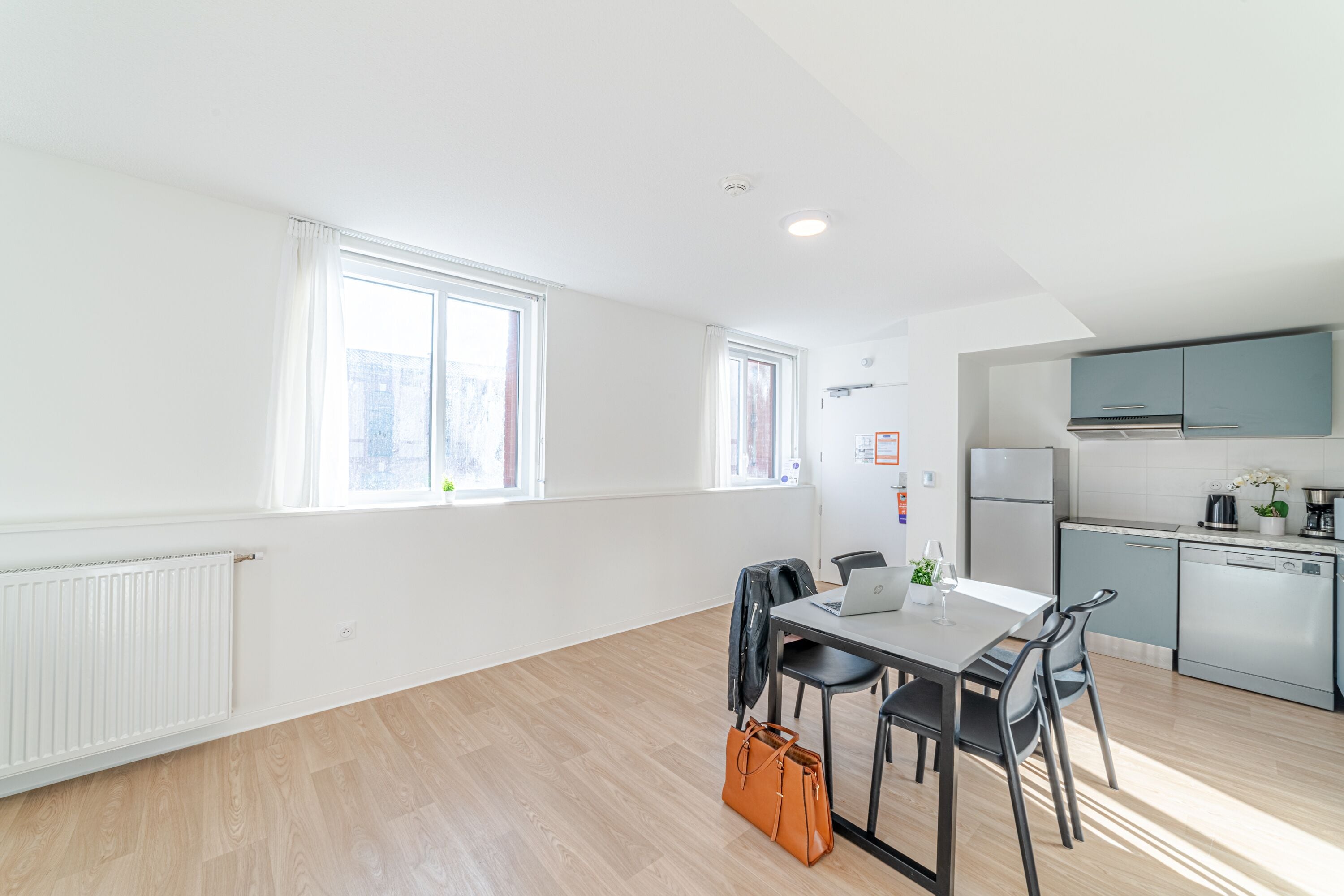 Een modern appartement met een eethoek, keuken en grote ramen.