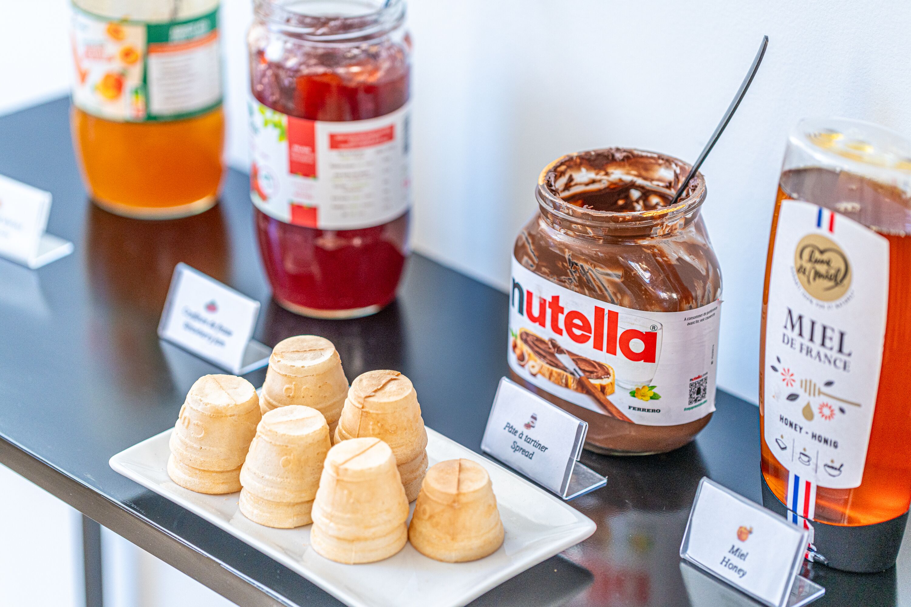 Una mesa con botes de Nutella, miel de France y pasteles de panal.