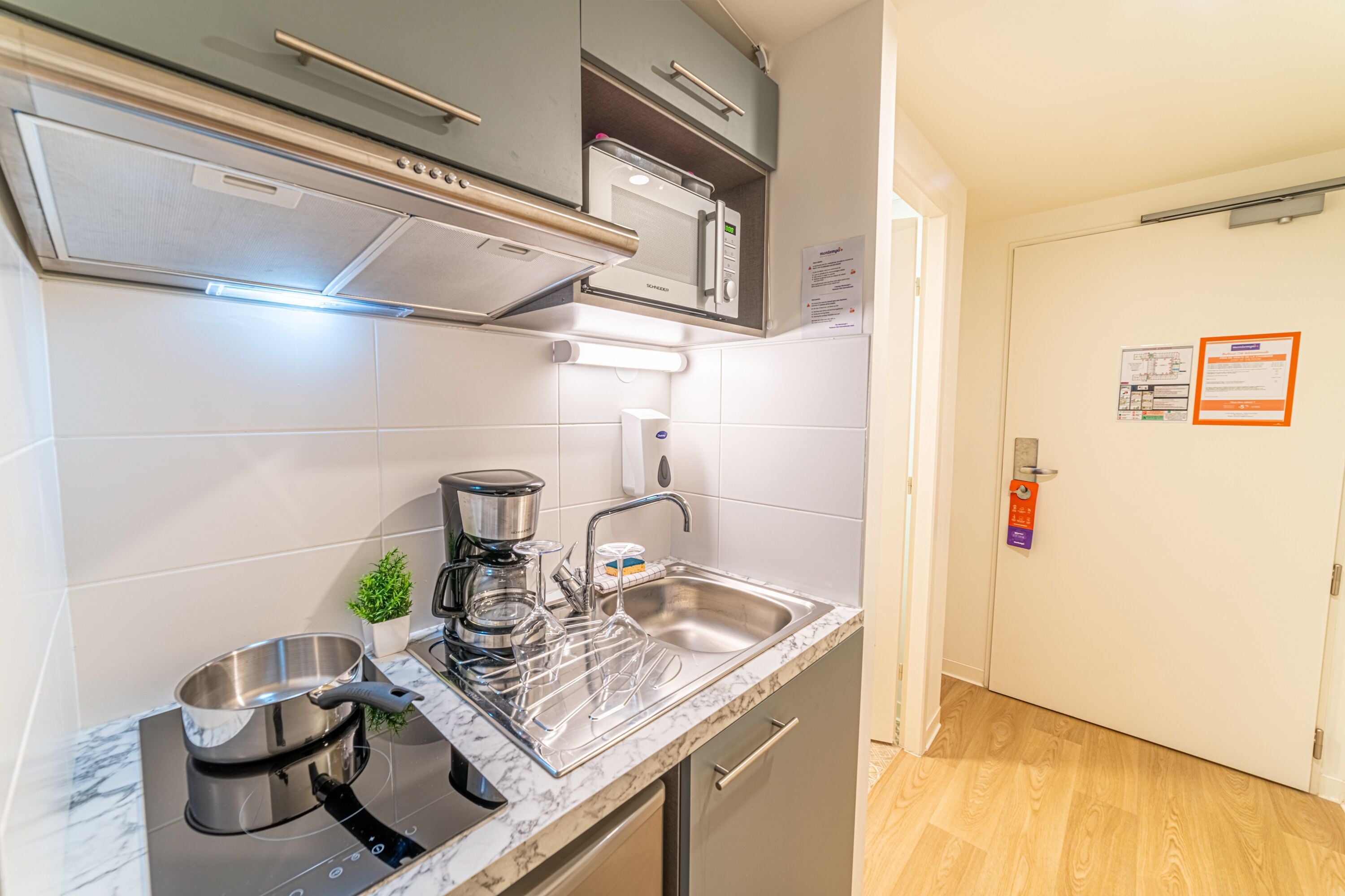 A modern kitchen with a built-in microwave, stainless steel sink, and a coffee maker.