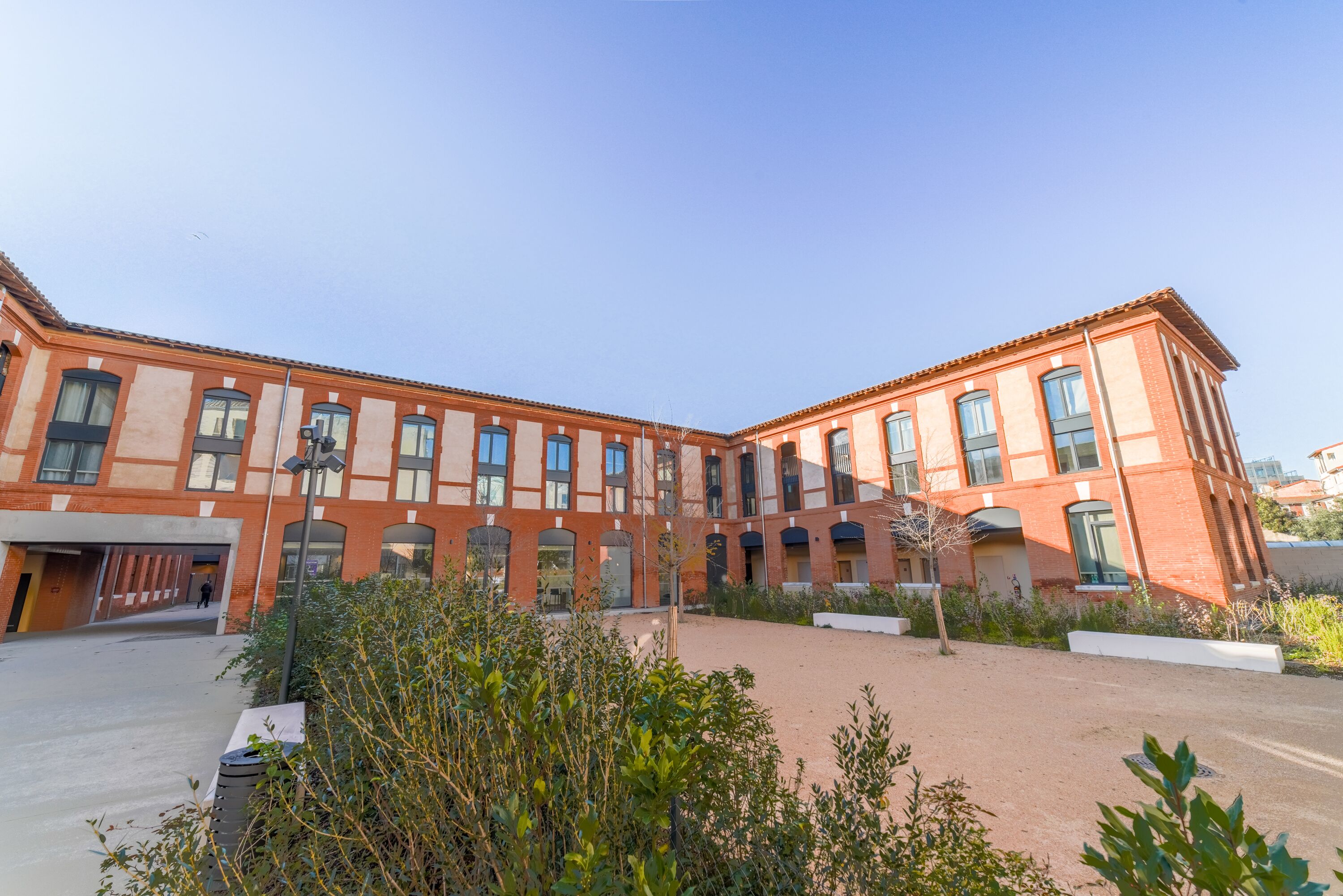 A red brick building with multiple windows and a covered entrance.