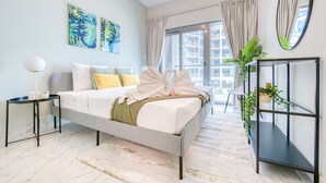 Quarto moderno com cama, mesa de cabeceira, espelho e vista para o exterior.