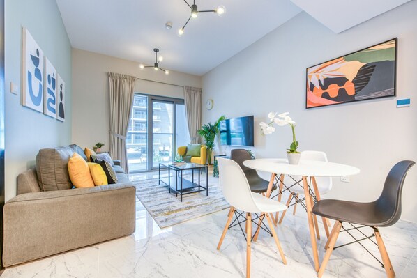 A modern living room with a sofa, dining table, chairs, and a TV.
