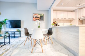 A modern kitchen with light wood cabinets, a built-in oven, and a countertop with a coffee machine.