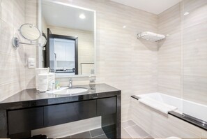 A modern bathroom with a black vanity, a large mirror, a bathtub, and beige tiled walls. - Cozy Studio in Damac Celestia A Dubai South by Deluxe Holiday Homes (Dubai)