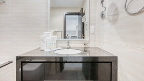 Uma casa de banho moderna com um espelho grande, lavatório e chuveiro.
