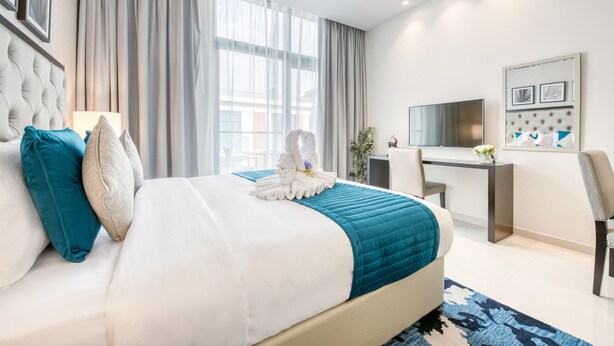 Quarto de hotel moderno com uma cama grande, uma mesa de escritório, televisão e vista para a cidade.