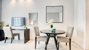 Uma sala de jantar moderna com uma mesa redonda, duas cadeiras, uma TV e um espelho grande na parede.