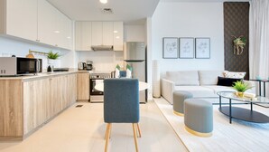 A modern kitchen with white cabinets, a built-in microwave, and a stainless steel refrigerator. - Spotless 1BR at UNA Town Square Dubailand by Deluxe Holiday Homes (Dubai)
