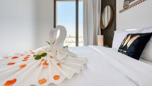 A hotel room with a neatly made bed, a large window, and a view of the cityscape. - Spotless 1BR at UNA Town Square Dubailand by Deluxe Holiday Homes (Dubai)
