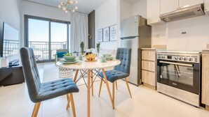 Eine moderne Küche mit Einbauofen, eine Essecke mit rundem Tisch und zwei Stühlen und ein großes Fenster mit Blick auf die Stadt.