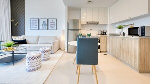 Ein modernes Wohnzimmer mit einer Couch, Hocker und einem Essbereich.