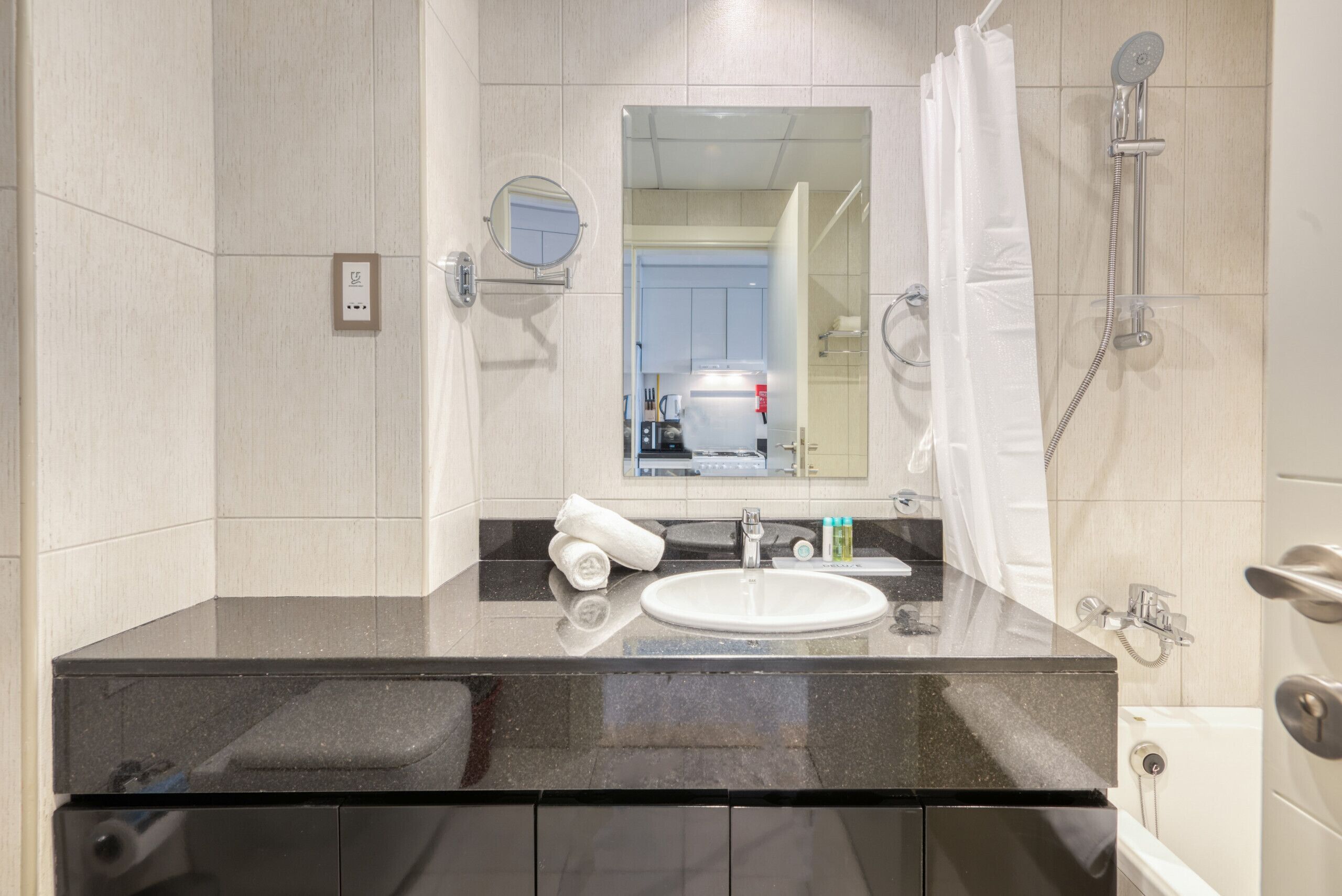 A modern bathroom with a black countertop, white sink, and a mirror above it.