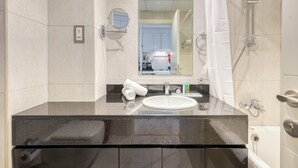 A modern bathroom with a black countertop, white sink, and a mirror above it. - Intimate Studio in Damac Ghalia Jumeirah Village Circle by Deluxe Holiday Homes (Dubai)