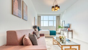 A modern living room with a sofa, coffee table, and artwork on the wall. - Intimate Studio in Damac Ghalia Jumeirah Village Circle by Deluxe Holiday Homes (Dubai)