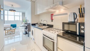 A modern kitchen with a gas stove, microwave, and sink. - Intimate Studio in Damac Ghalia Jumeirah Village Circle by Deluxe Holiday Homes (Dubai)