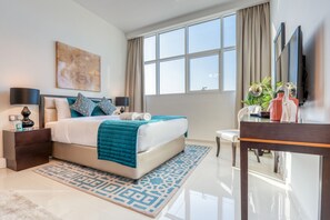 Een moderne hotelkamer met een groot bed, een bureau, een stoel, een televisie en een raam met gordijnen.