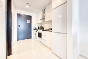 A modern kitchen with white cabinets, a built-in oven, a microwave, and a refrigerator.