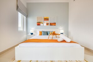 Quarto de hotel moderno com uma cama grande, mesa de cabeceira com abajur e janela com vista para edifícios.