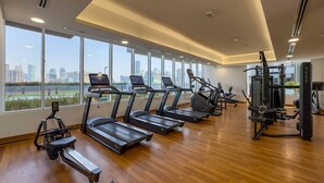A gym with treadmills, exercise bikes, and weight machines. - Sky-High Studio, Few Minutes Walk from Circle Mall and Near the Park (Dubai)