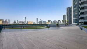 A rooftop terrace with a city skyline in the background, featuring modern buildings and a clear sky. - Sky-High Studio, Few Minutes Walk from Circle Mall and Near the Park (Dubai)
