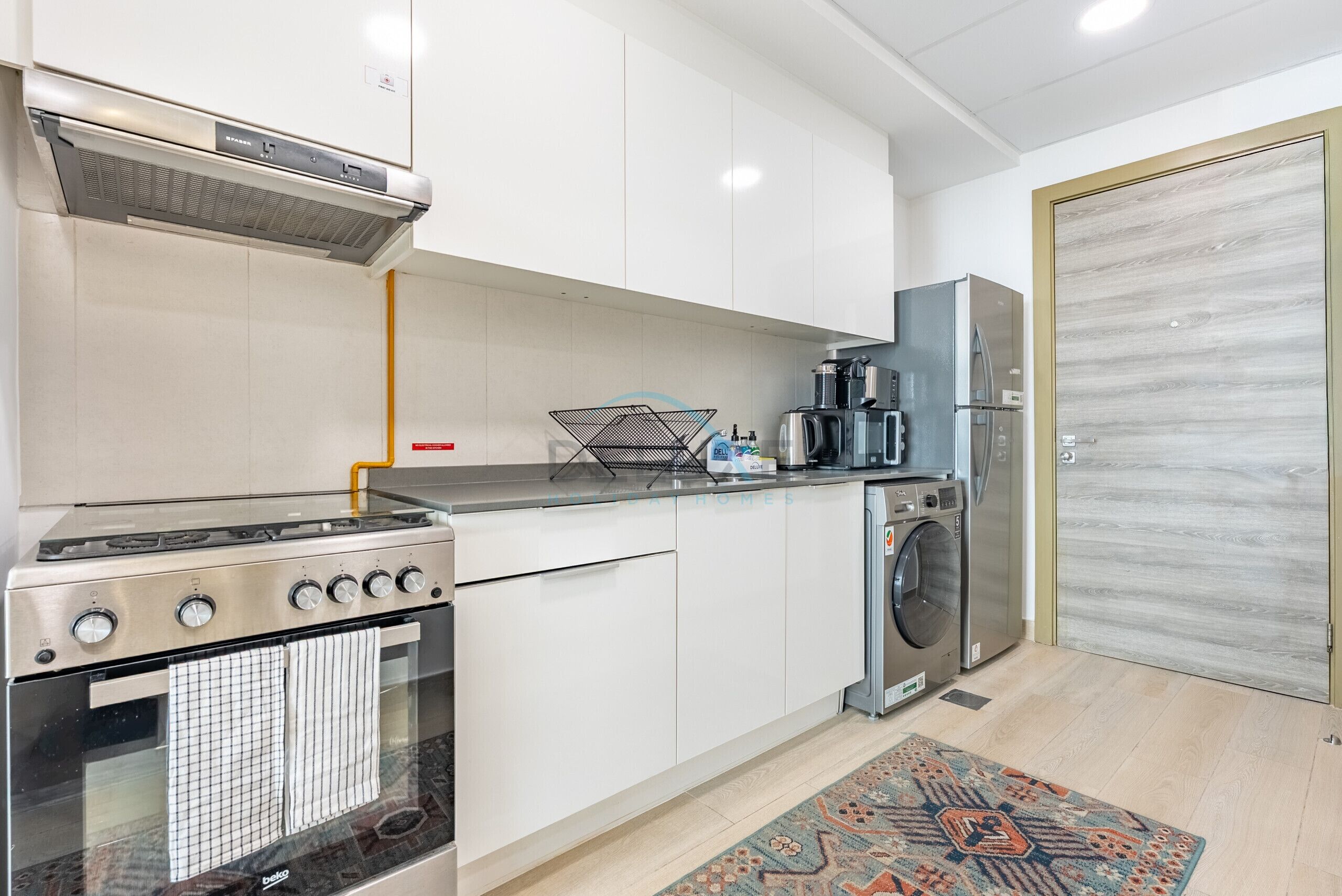 A modern kitchen with a stove, oven, washing machine, and refrigerator.