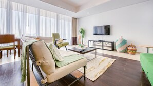Uma sala de estar moderna com sofá, poltrona, mesa de centro e TV fixada na parede.