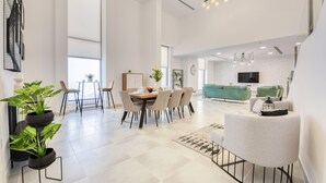 A spacious living area with a dining table, chairs, a sofa, and a TV. - Outstanding 3BR at Sadaf 7 JBR by Deluxe Holiday Homes (Dubai)