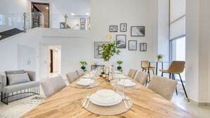 A spacious dining area with a long wooden table set for a meal, surrounded by modern chairs. - Outstanding 3BR at Sadaf 7 JBR by Deluxe Holiday Homes (Dubai)