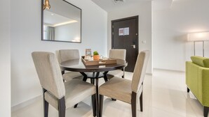 A modern dining area with a round table, four chairs, a mirror, and a door with a notice. - Luxury 1BR at DAMAC Celestia A Dubai South by Deluxe Holiday Homes (Dubai)