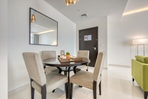 A modern dining area with a round table, four chairs, a mirror, and a door with a notice.