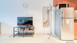 A modern kitchen with a refrigerator, microwave, and a TV on a stand.