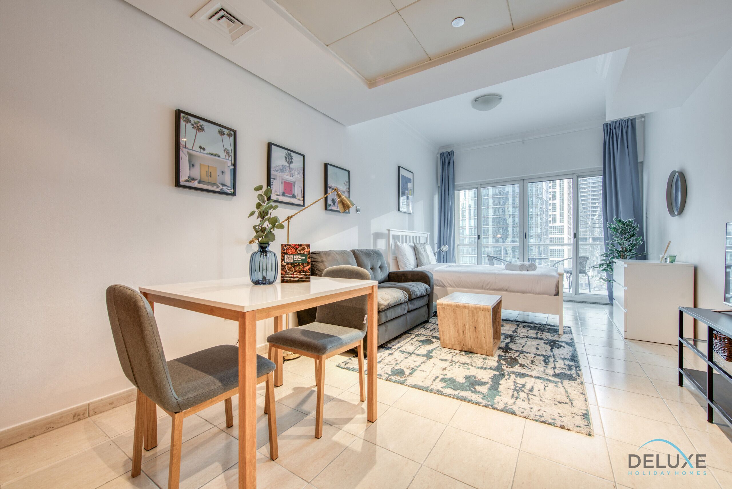 Una sala moderna con una mesa de comedor, sofá y vistas de la ciudad a través de amplios ventanales.