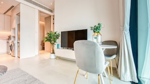 Una sala de estar moderna con un televisor de pantalla plana, un sofá gris, una mesa de comedor y una planta en maceta.