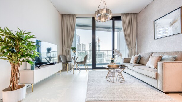 Una sala de estar moderna con un sofá, una mesa de centro, un televisor y un ventanal con cortinas.