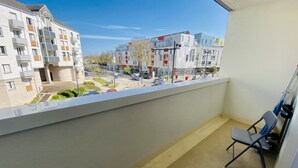 Ein Balkon mit Blick auf ein Wohngebiet, einschließlich mehrstöckiger Gebäude und geparkter Autos.