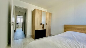 Ein modernes Schlafzimmer mit einem großen Bett, einem Holzschrank und einem Flur, der zum Badezimmer führt.