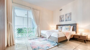 Una camera da letto con un letto grande, un comodino, una finestra con tende e vista sul verde.
