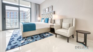 Ett modernt hotellrum med en stor säng, en sittgrupp och utsikt över stadsbilden genom stora fönster från golv till tak.
